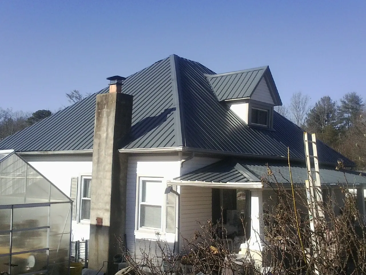 Dark blue standing seam metal roof on a white farmhouse with dormer — Slate & Tile Roof Repair by Roofing Brothers in Pemberton