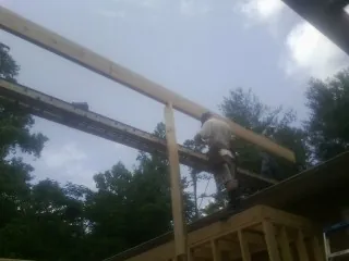 Carpenter setting a ridge beam over a new addition frame — Ice Dam Removal by Roofing Brothers in Pemberton