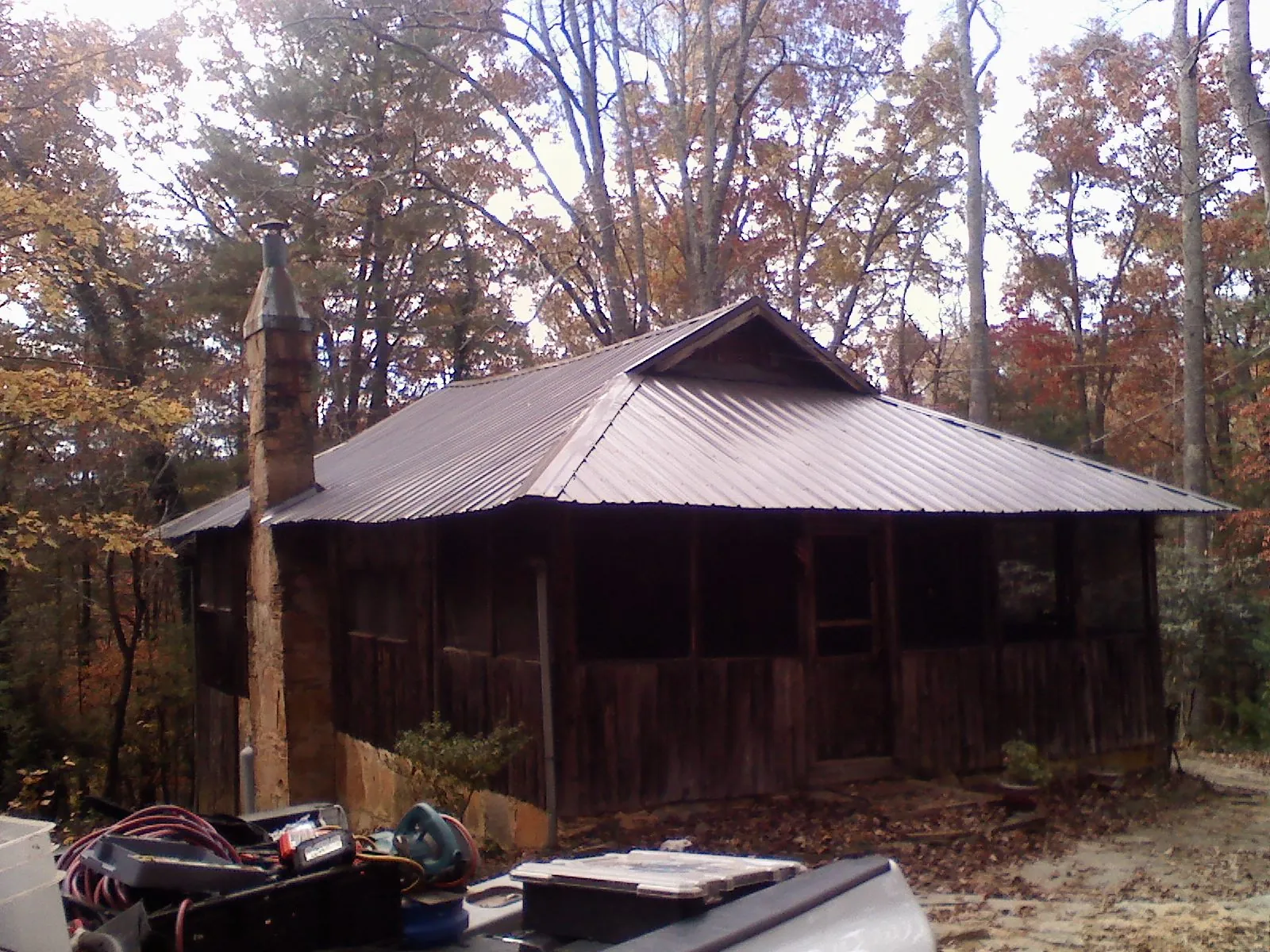 Brown metal hip roof on an old cabin with a stone chimney in Pemberton