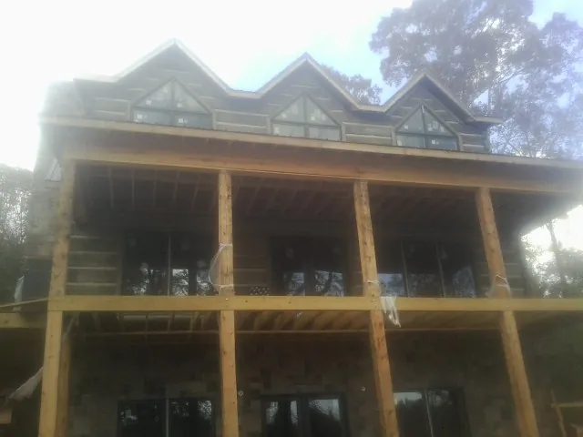 Dormers and porch framing on a large log home under construction — Roof Coating work by our crew in Pemberton