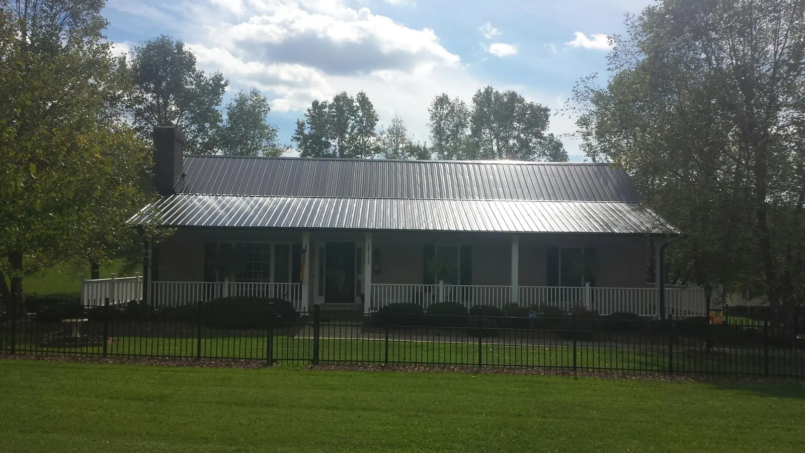 Gray metal roof on a brick ranch with a full width front porch — Gutter Guard Installation work by our crew in Pemberton