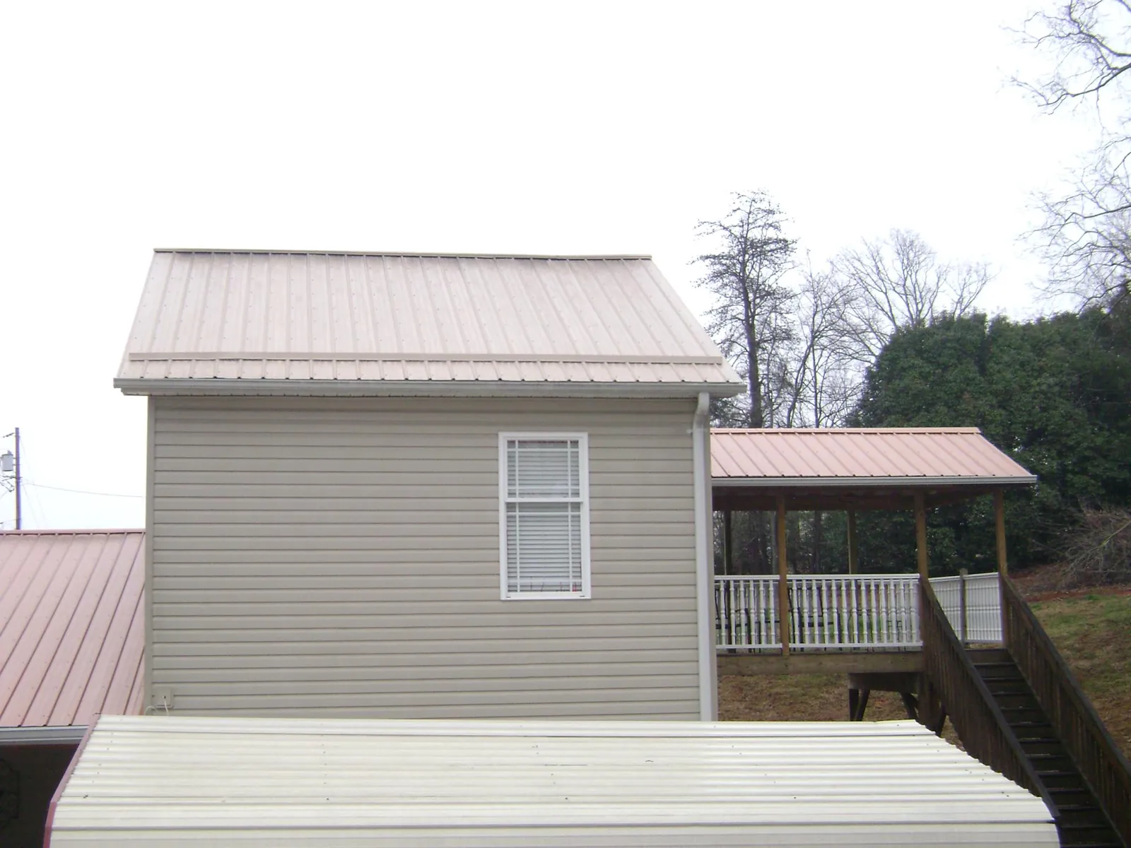 Tan metal roofs on a two story addition and attached porch, from a Roof Replacement job in Pemberton