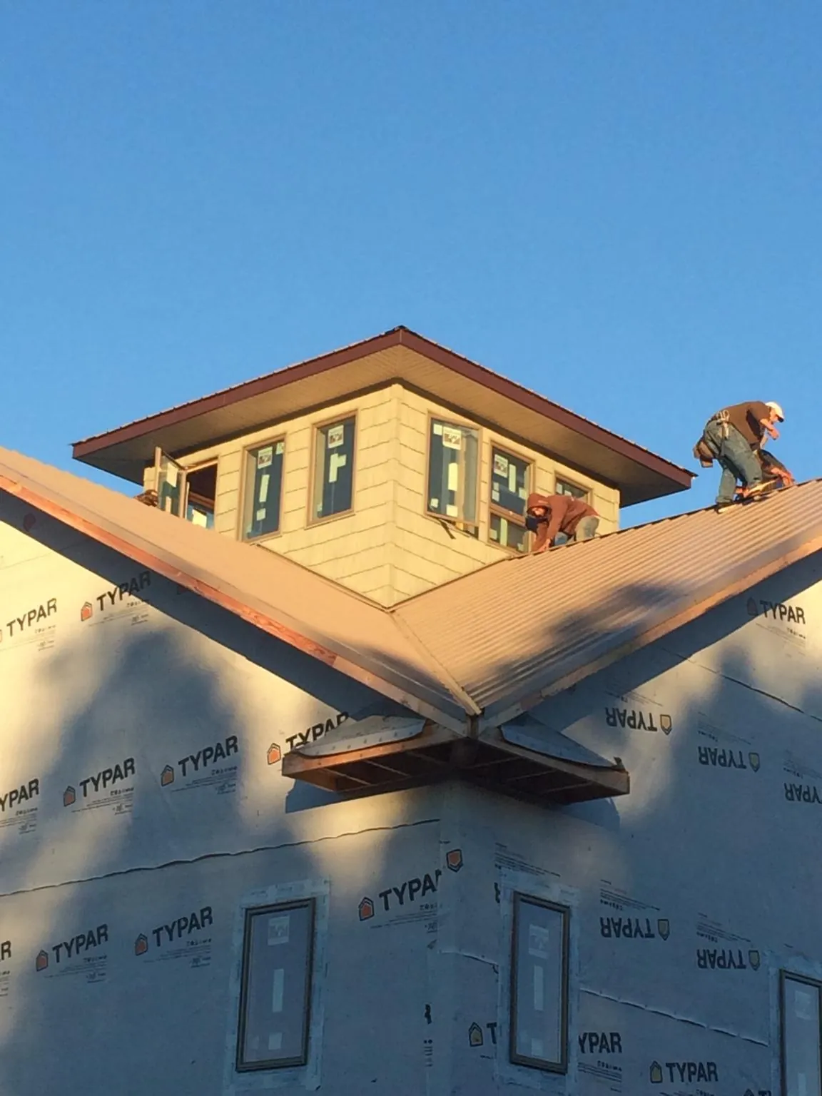 Roofers working around a rooftop cupola on a new metal roof at sunset — Roof Waterproofing in Pemberton by Roofing Brothers